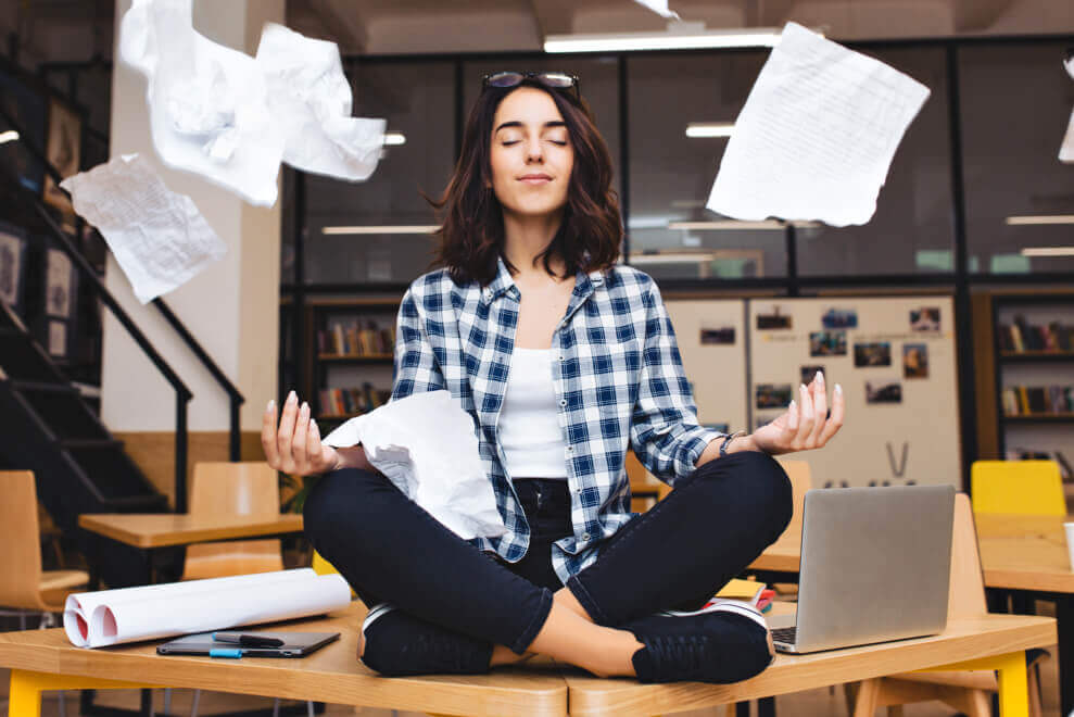 mujer sobre mesa en posición yoga, simulando su bienestar emocional